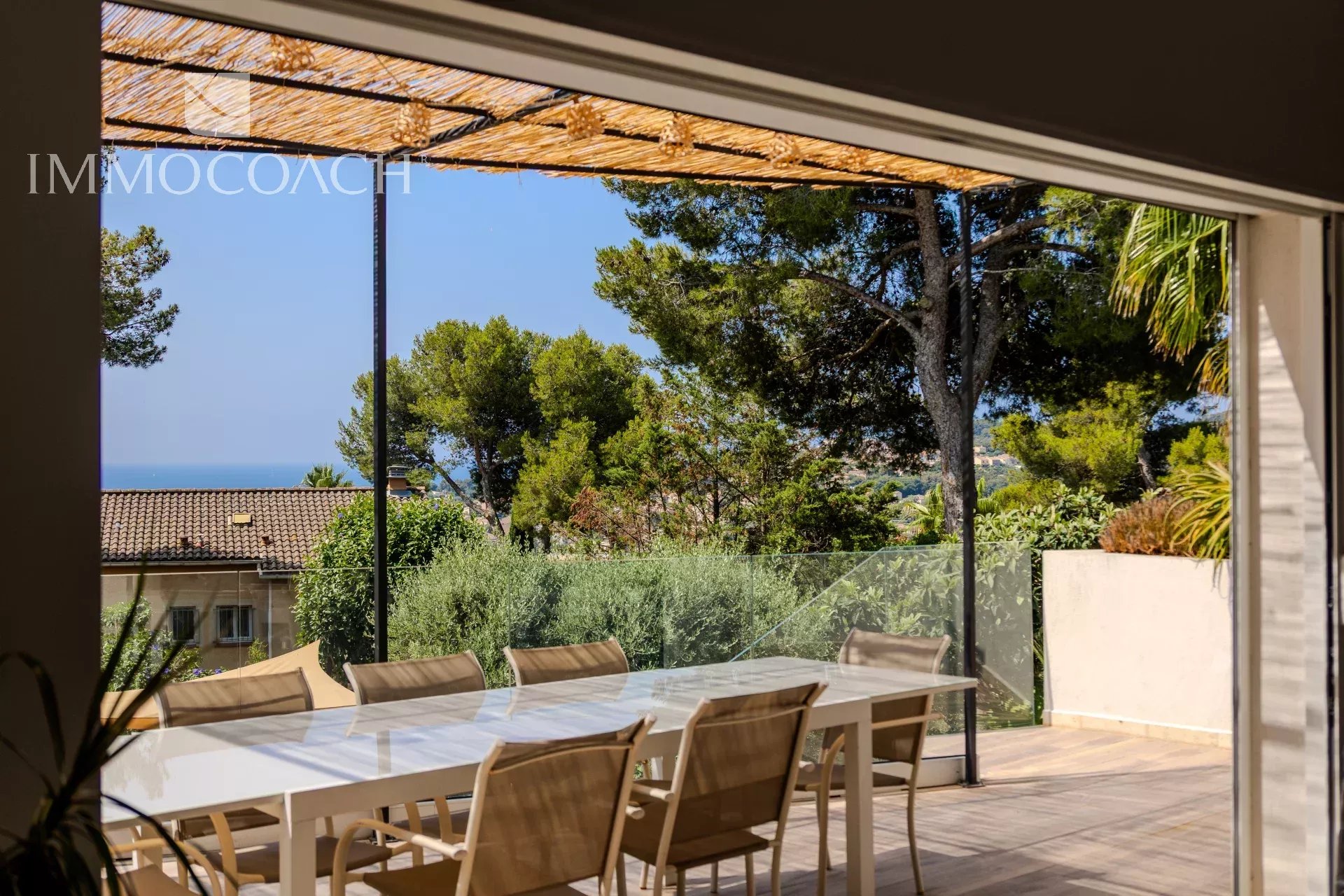 Vue d'une terrasse avec une table à manger et des chaises, entourée de verdure et d'arbres à Carqueiranne.