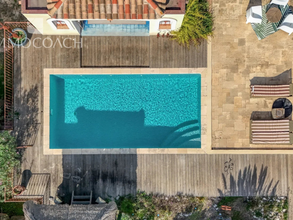 Aerial view of the swimming pool of a neo-Provençal villa with a wooden terrace in Bormes-les-Mimosas.