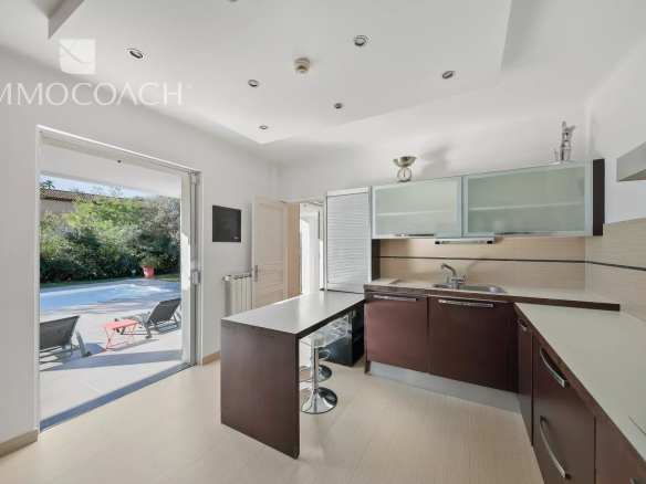 Cuisine moderne avec plan de travail et accès à la terrasse, vue sur la piscine.