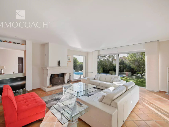 Intérieur d'une villa à Carqueiranne avec salon lumineux, cheminée et vue sur le jardin.