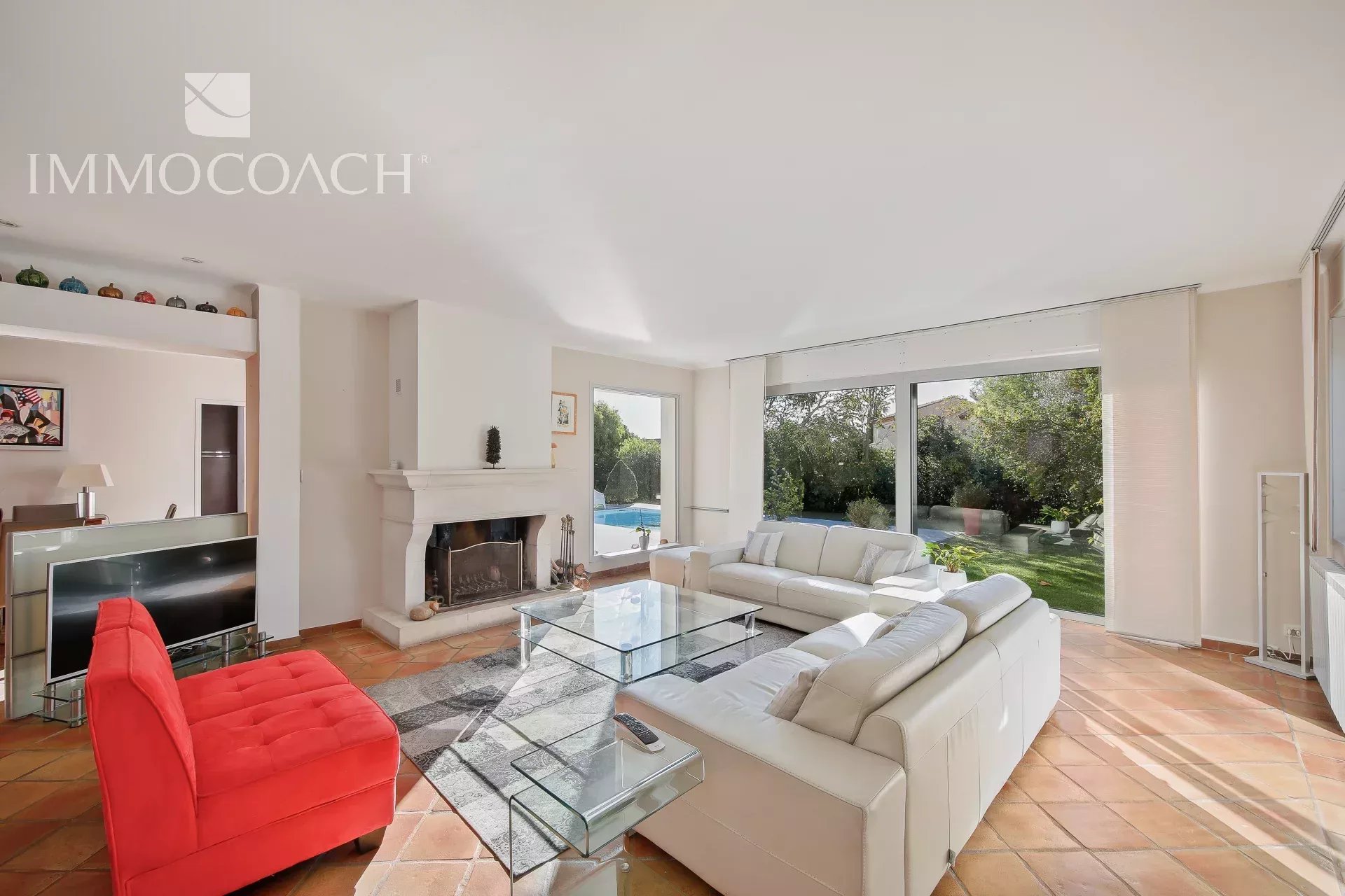 Salon lumineux d’une villa à Carqueiranne Intérieur d'une villa à Carqueiranne avec salon lumineux, cheminée et vue sur le jardin.