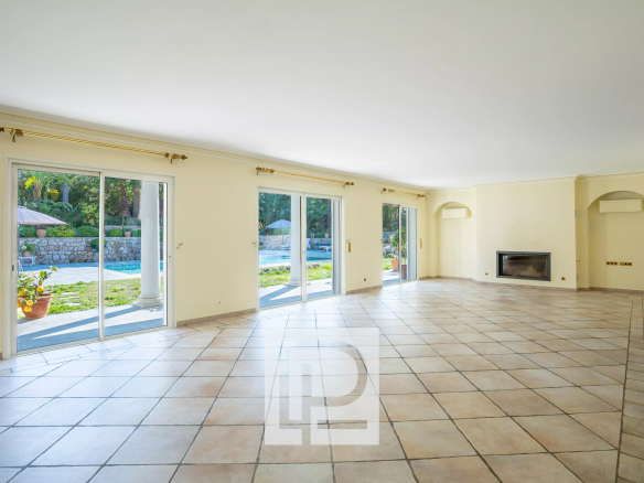 Bright empty living room with beige tiled floor and sliding glass doors to a pool and garden outside.