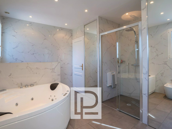 Contemporary bathroom with a corner soaking tub, glass shower enclosure, bidet, and marble walls.