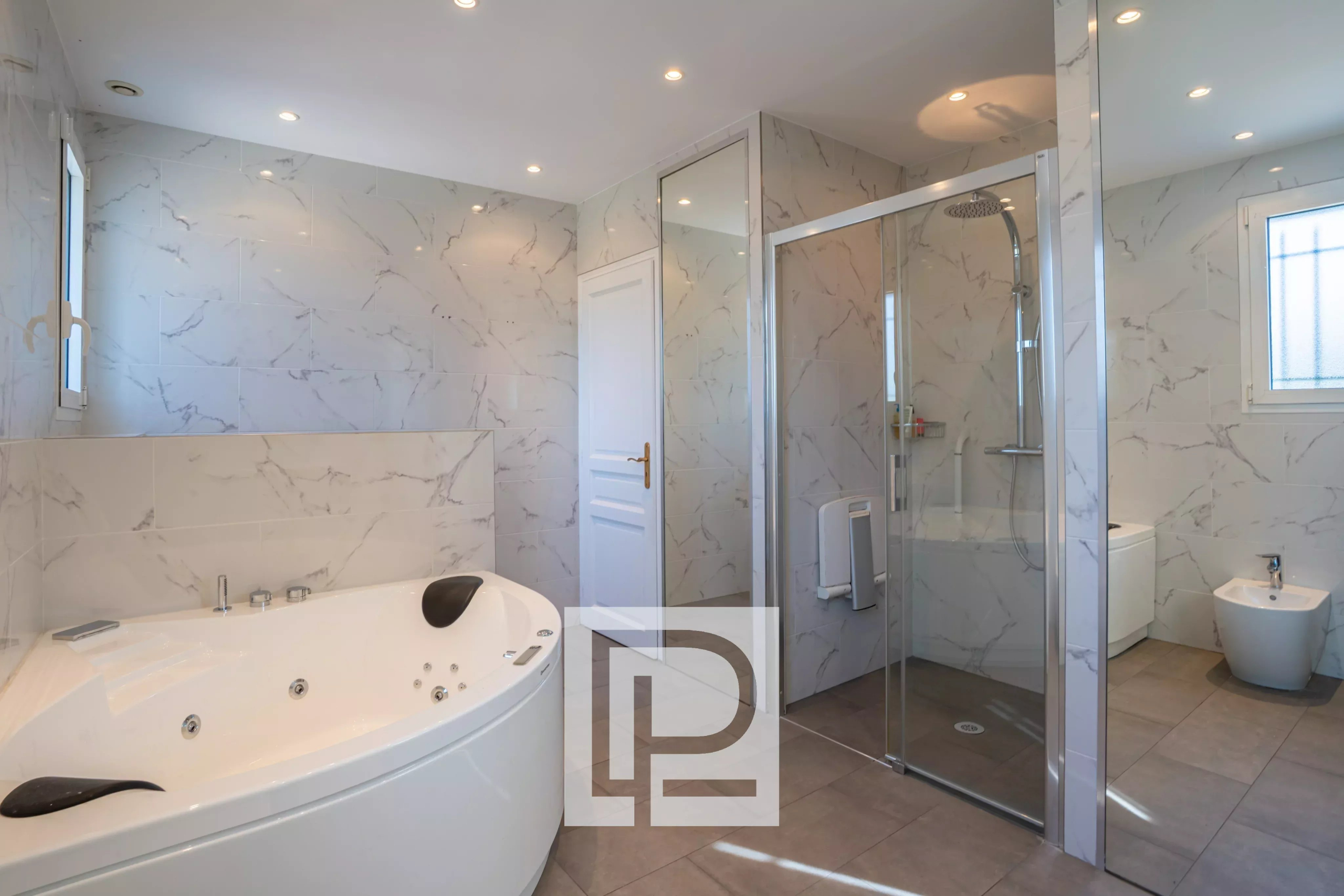 Contemporary bathroom with a corner soaking tub, glass shower enclosure, bidet, and marble walls.