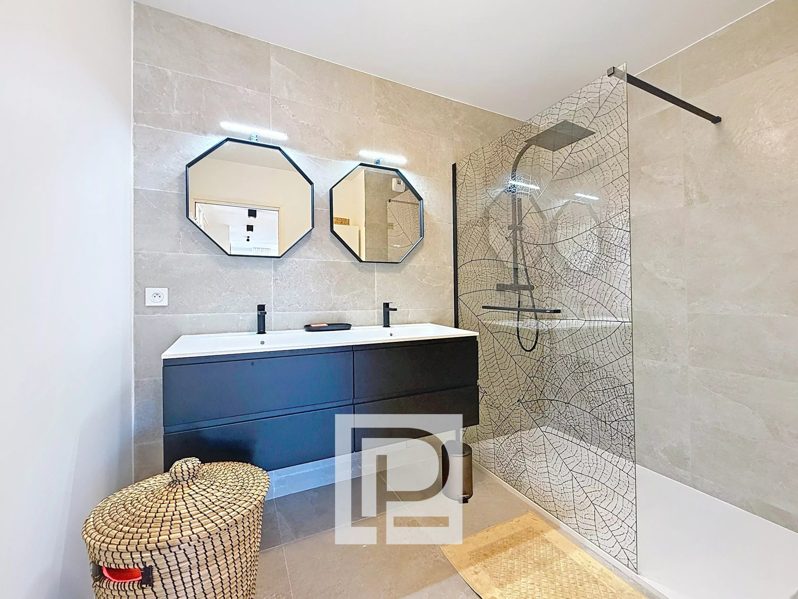 Modern bathroom with a dark floating double sink vanity, two octagonal mirrors, and a patterned glass shower enclosure.