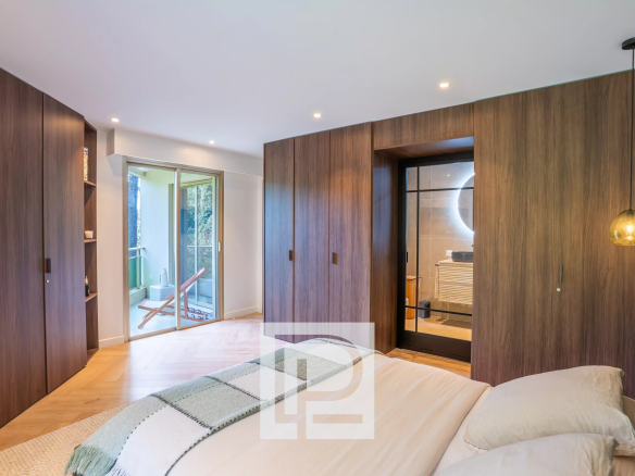 Modern bedroom with dark wood wardrobes along the walls, a bed in the foreground, and a balcony door to the left.