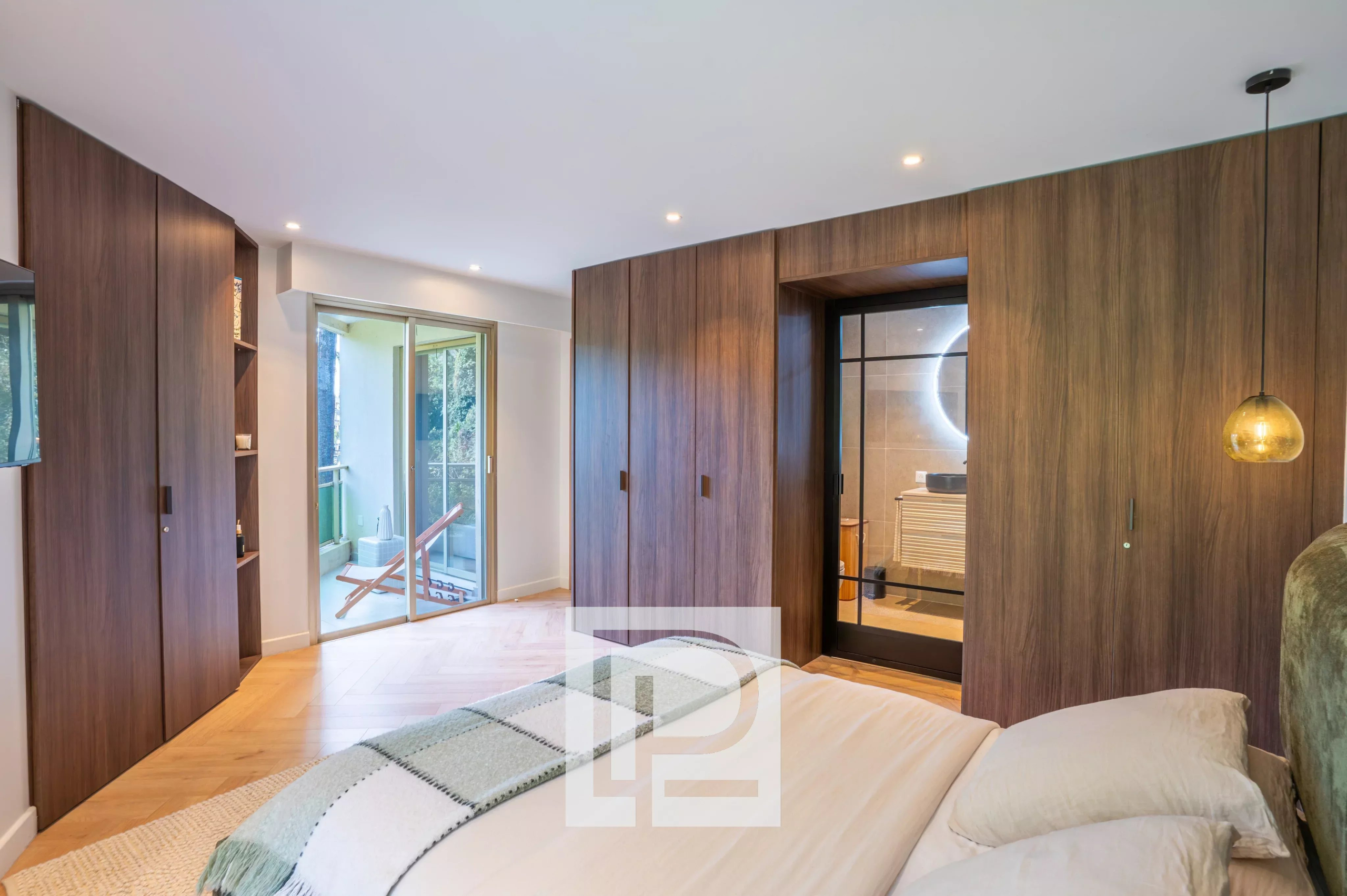 Modern bedroom with dark wood wardrobes along the walls, a bed in the foreground, and a balcony door to the left.