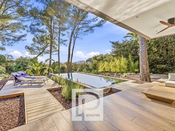 Modern backyard with a rectangular pool, wooden deck, and purple lounge chairs under a shaded patio.