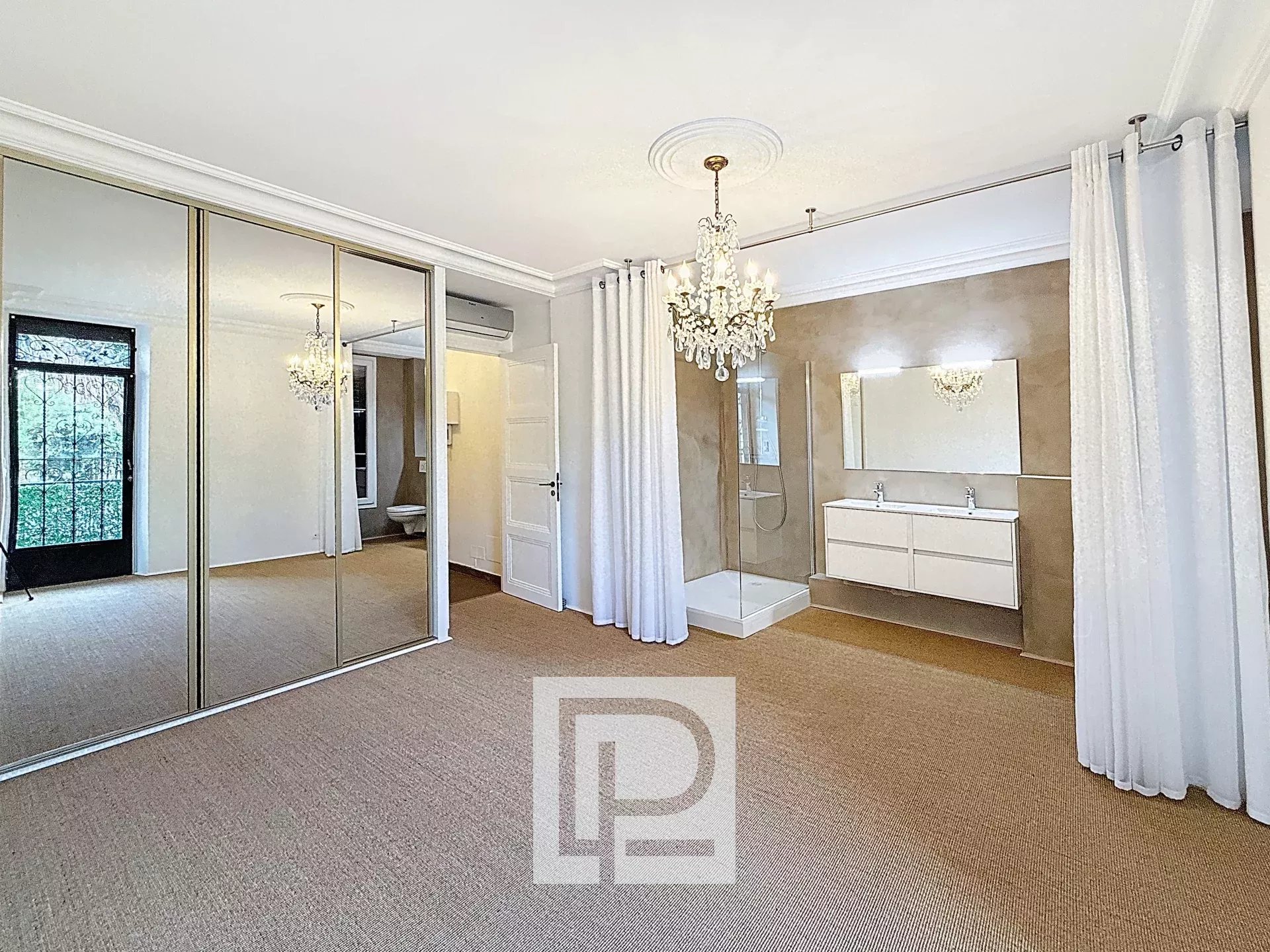 Bedroom with a large mirrored wardrobe, crystal chandelier, white drapes, and beige carpet.