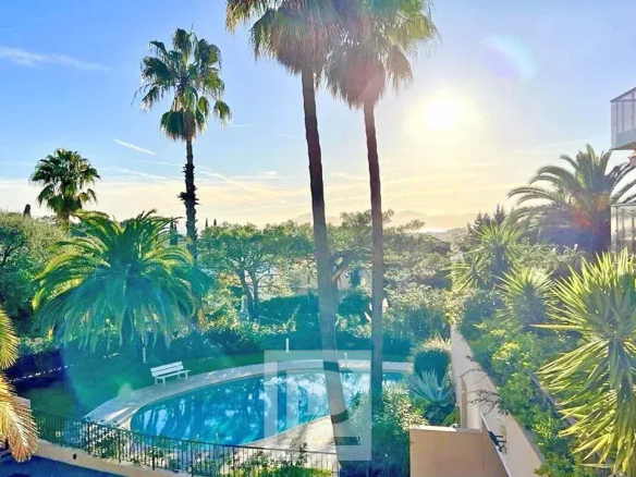 Vue sur la piscine et les palmiers dans un quartier résidentiel au Cannet, avec ciel ensoleillé.