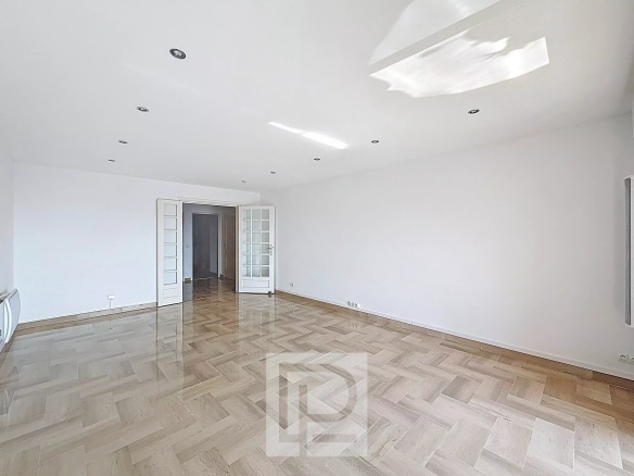Intérieur d'un appartement lumineux avec un sol en parquet et des portes-fenêtres