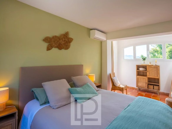 Chambre d'une villa provençale rénovée avec des murs verts et des meubles en bois à Mougins.