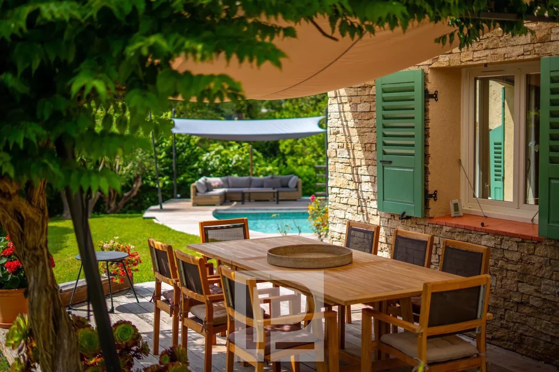 Terrasse de villa provençale à Mougins Terrasse en bois avec table à manger et piscine, entourée de verdure dans une villa provençale à Mougins.