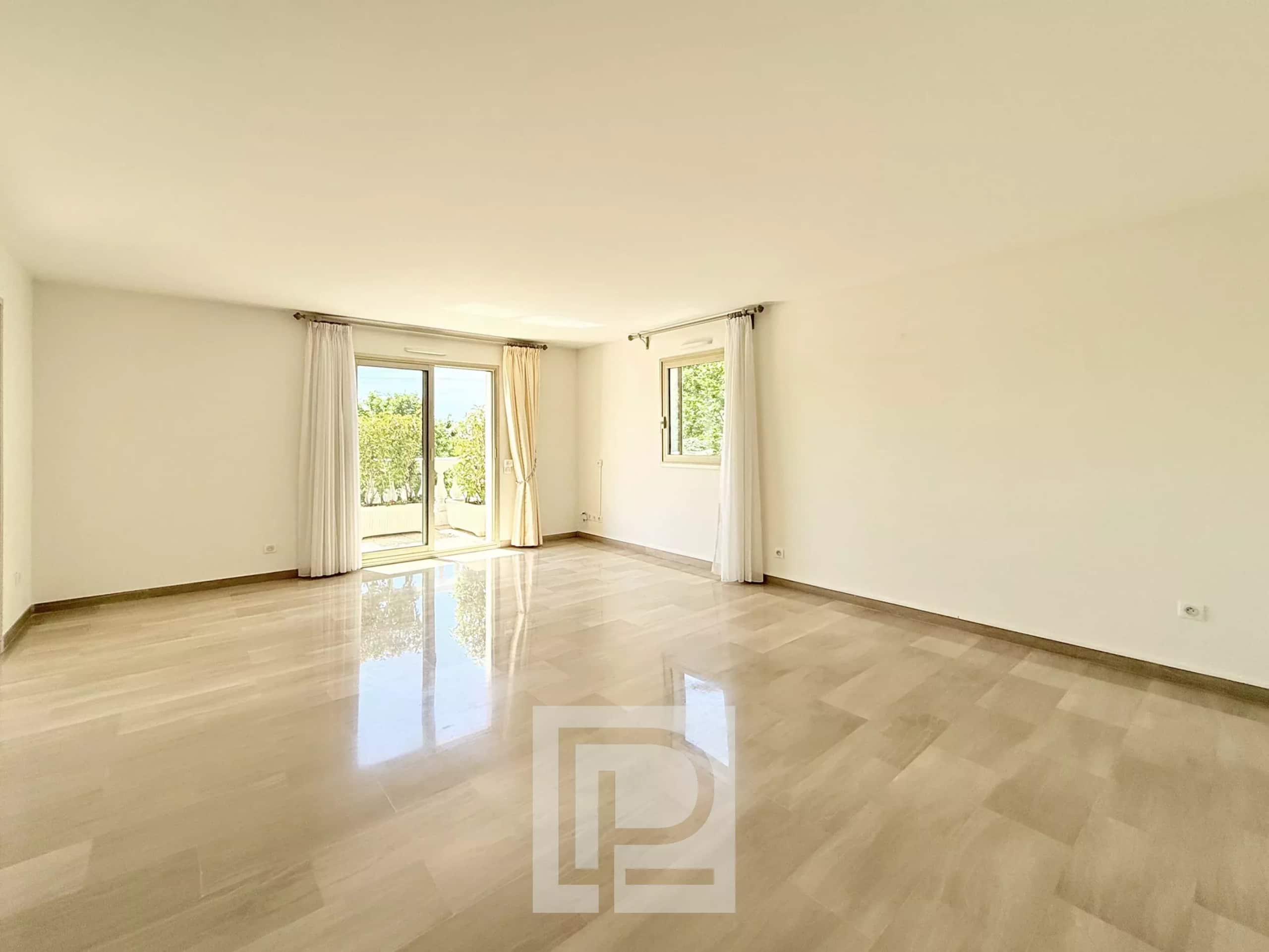 Interior of a spacious apartment with marble floor and large windows letting in light.