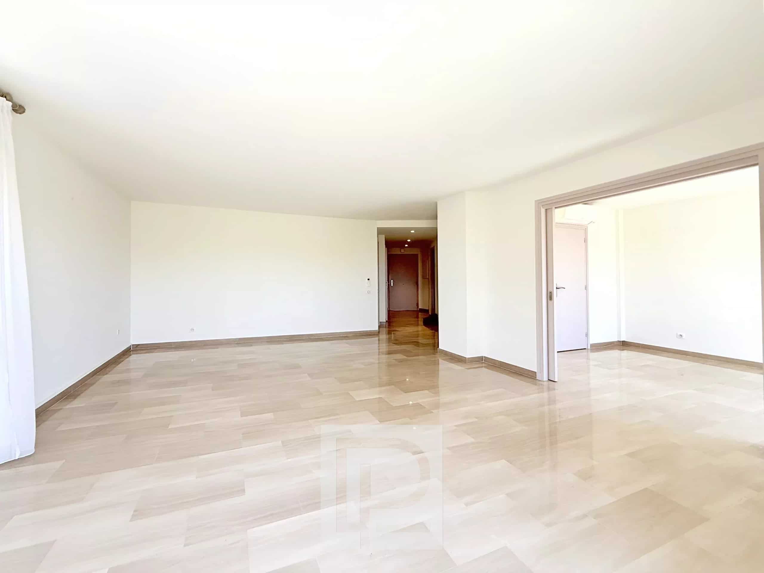 Interior of a spacious apartment with marble flooring and light-colored walls, without furniture.
