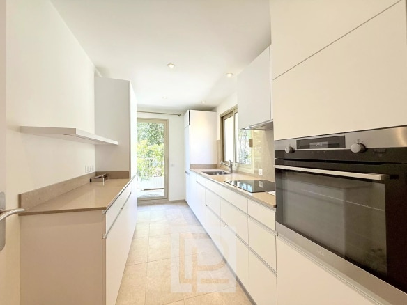 Modern and bright kitchen with white furniture and access to a terrace.