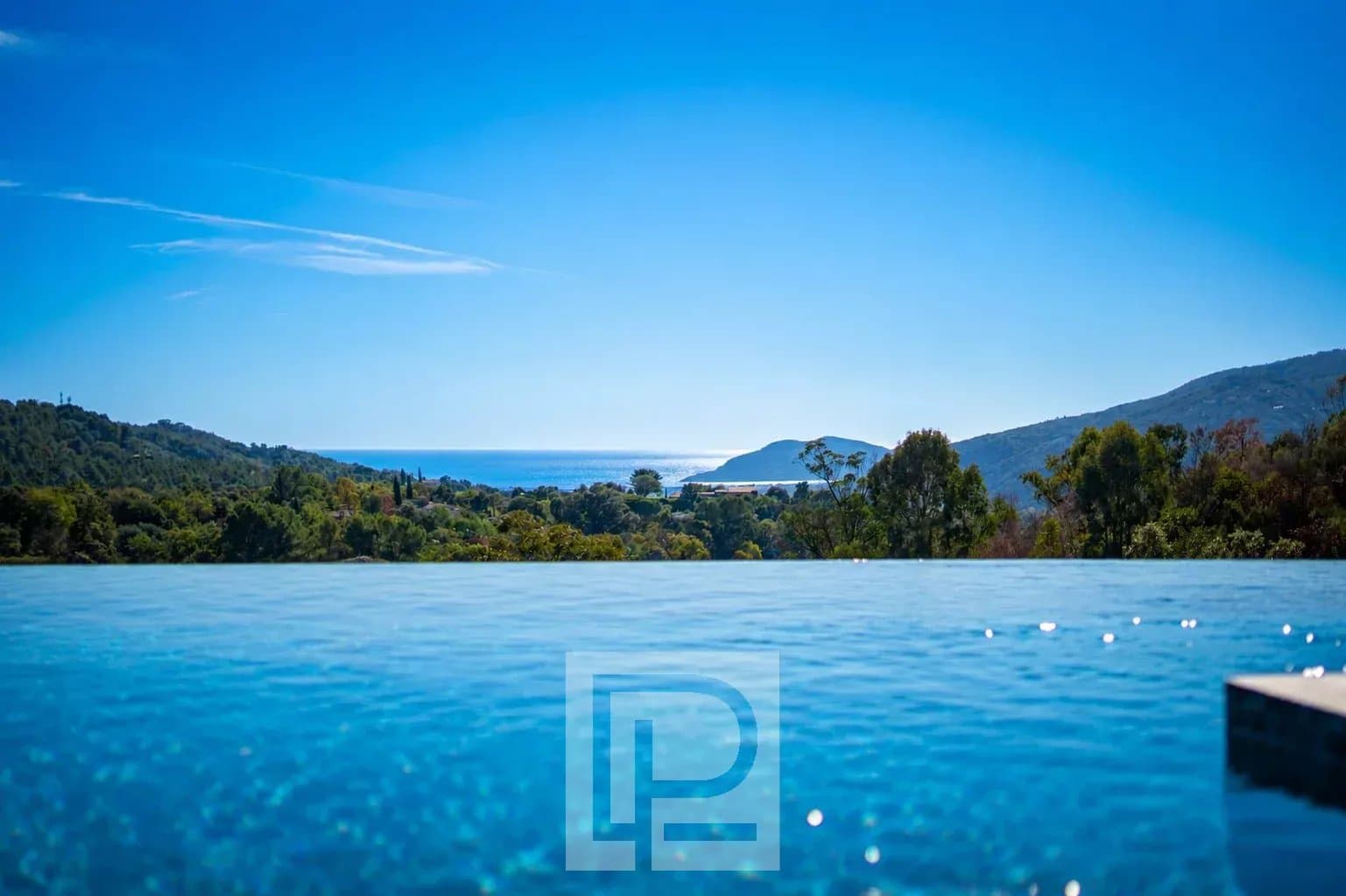Panoramic views of the sea and hills from an infinity pool.