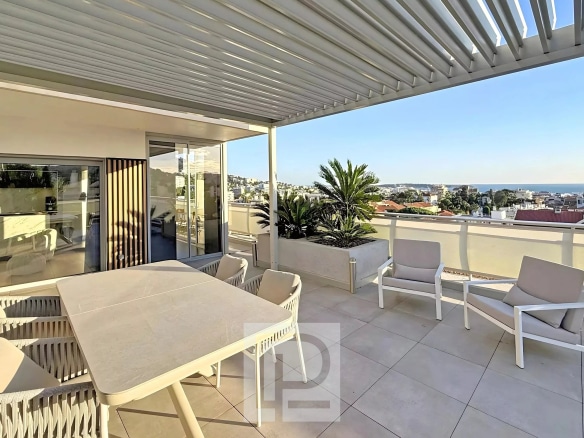 Terrasse d'un appartement rénové avec vue sur Cannes et mobilier moderne.