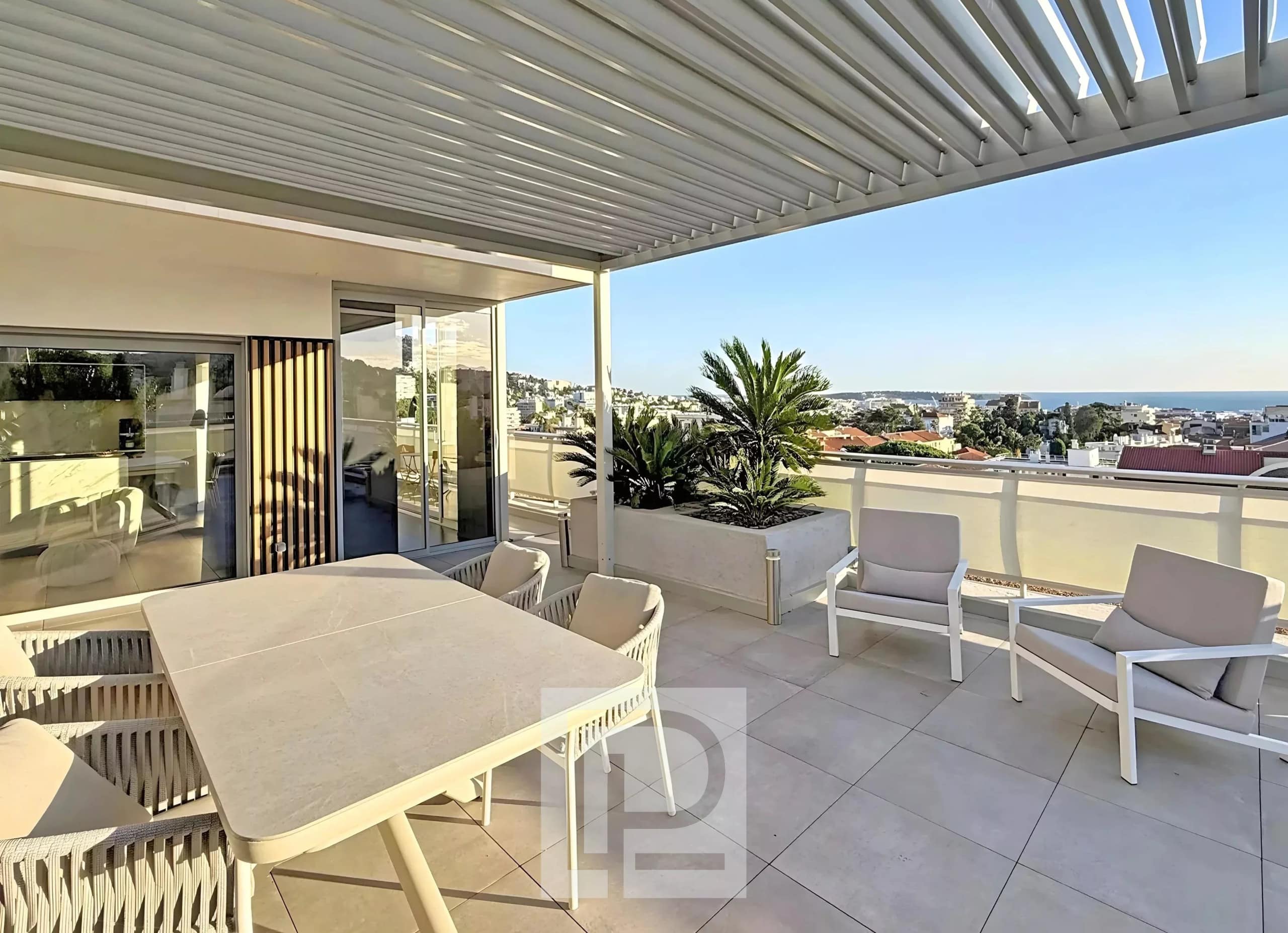 Terrasse d'un appartement rénové avec vue sur Cannes et mobilier moderne.