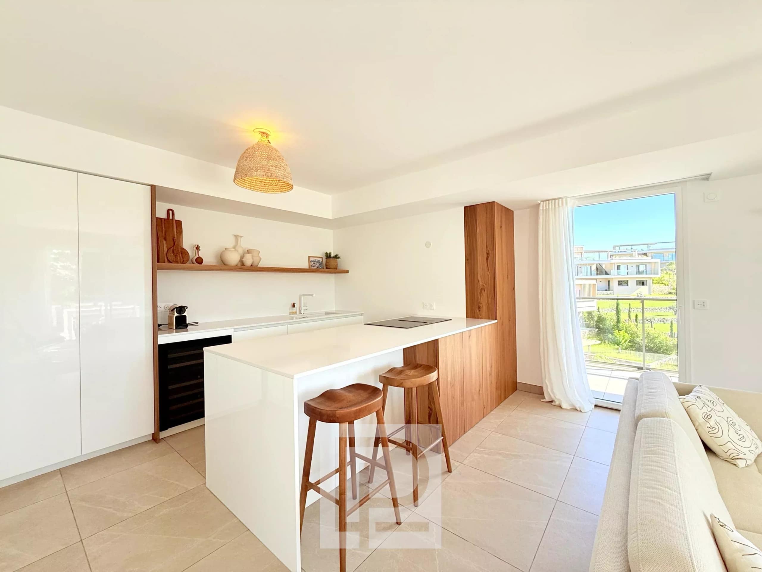 Cuisine moderne et lumineuse avec bar, vue sur l'extérieur dans un appartement à Mougins.