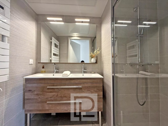 Salle de bain moderne avec double vasque et douche dans un appartement à Mougins.