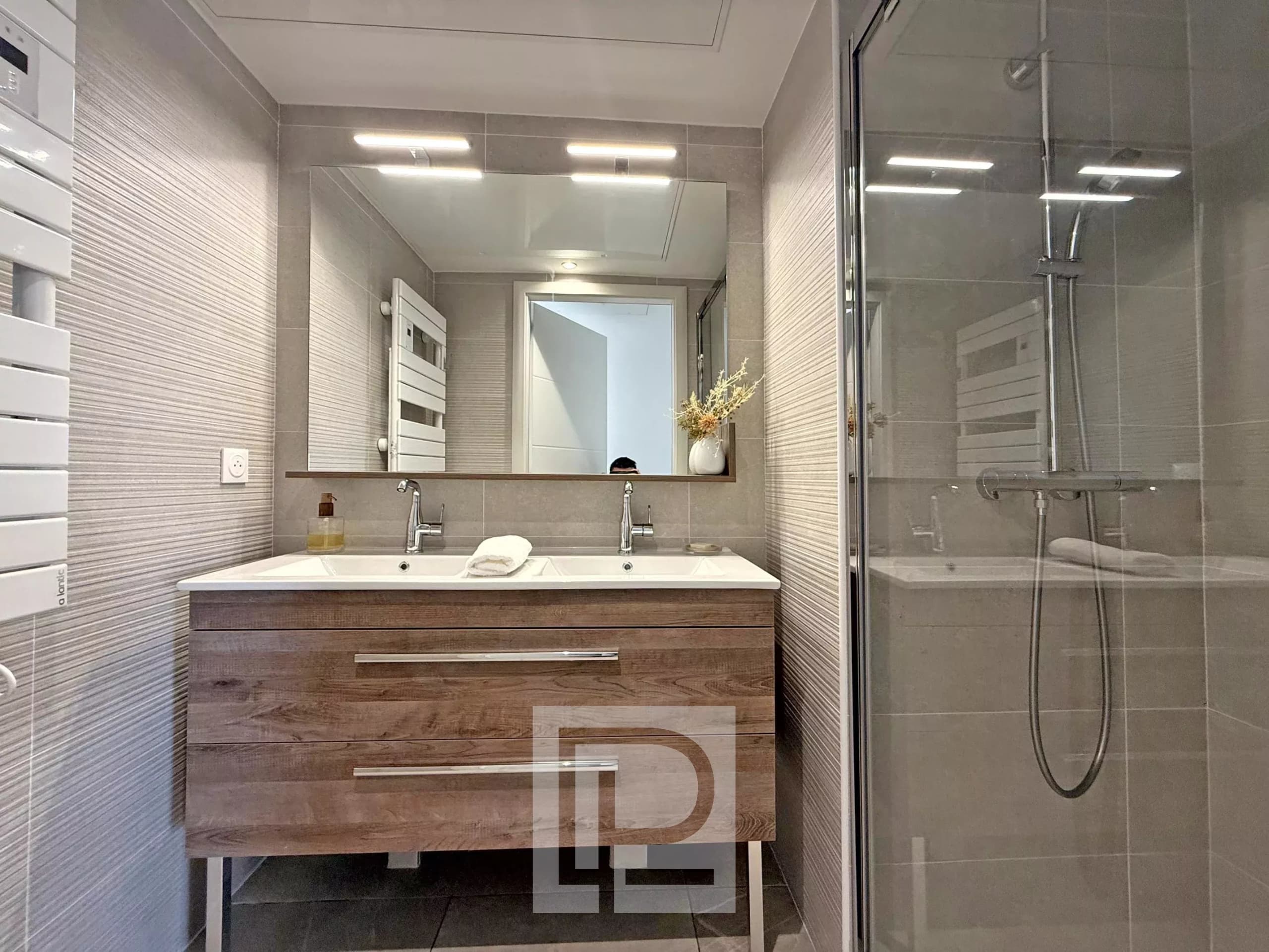 Salle de bain moderne avec double vasque et douche dans un appartement à Mougins.