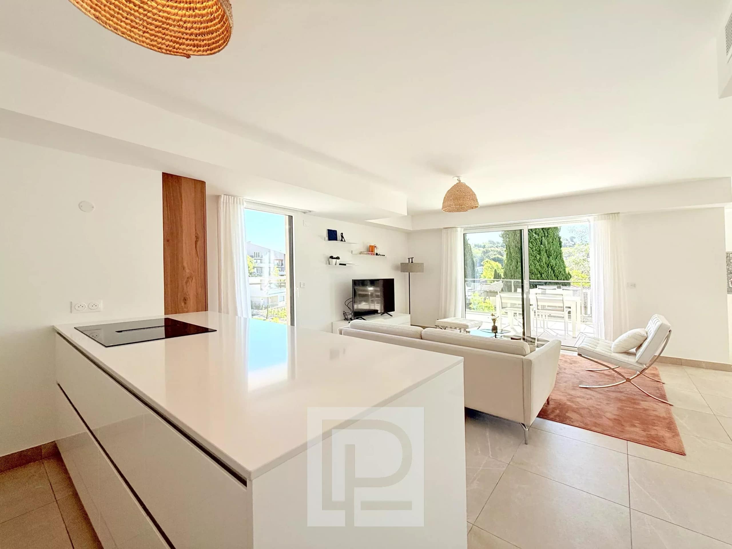 Intérieur d'un appartement moderne avec cuisine ouverte et salon lumineux, accès à un balcon.
