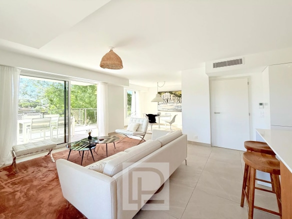 Intérieur d'un appartement moderne avec salon lumineux et accès à un balcon.