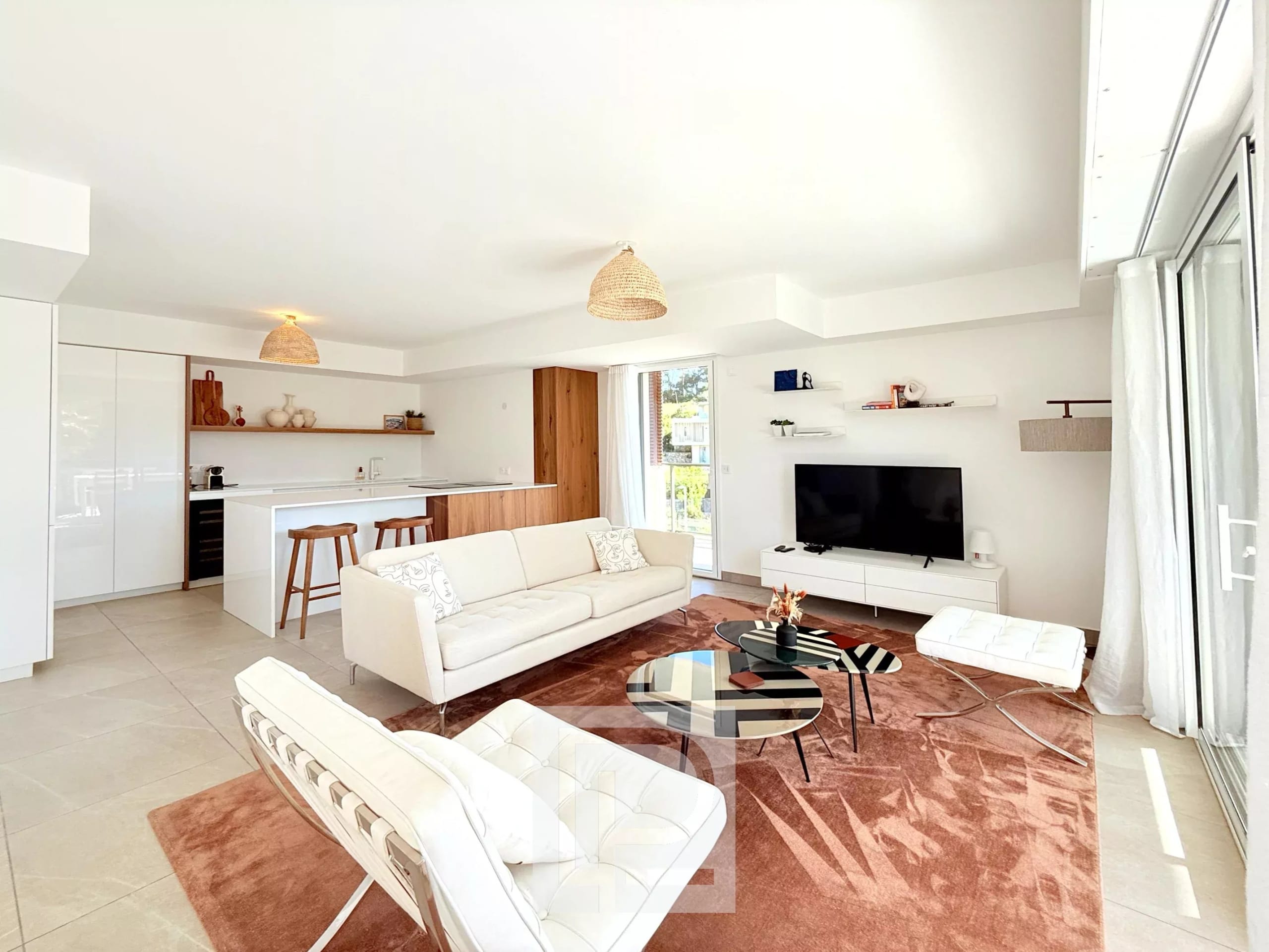 Intérieur d'un appartement moderne avec salon, cuisine ouverte et accès à un balcon.