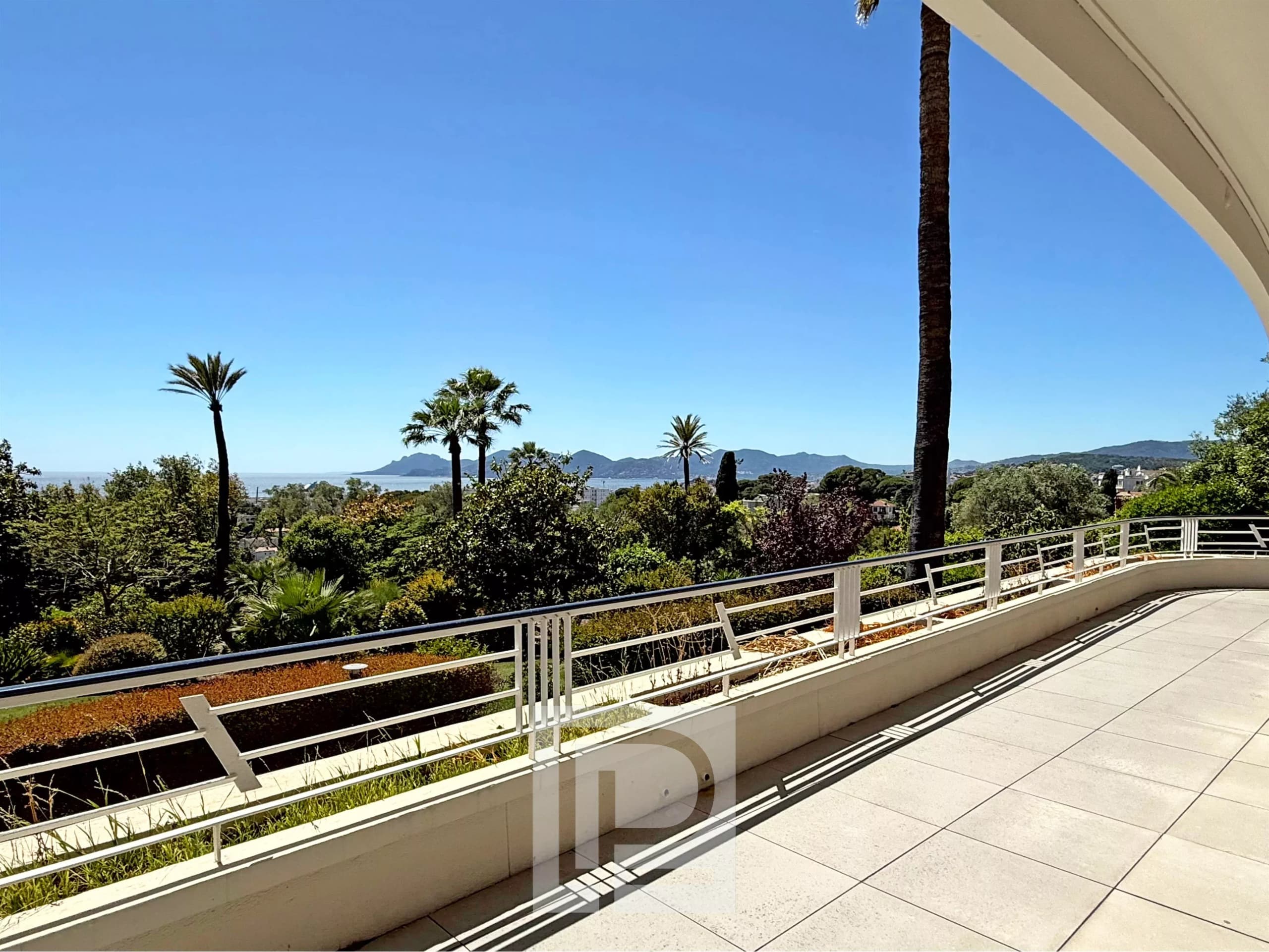 Terrace of an apartment in Cannes with views of the sea and the green park.