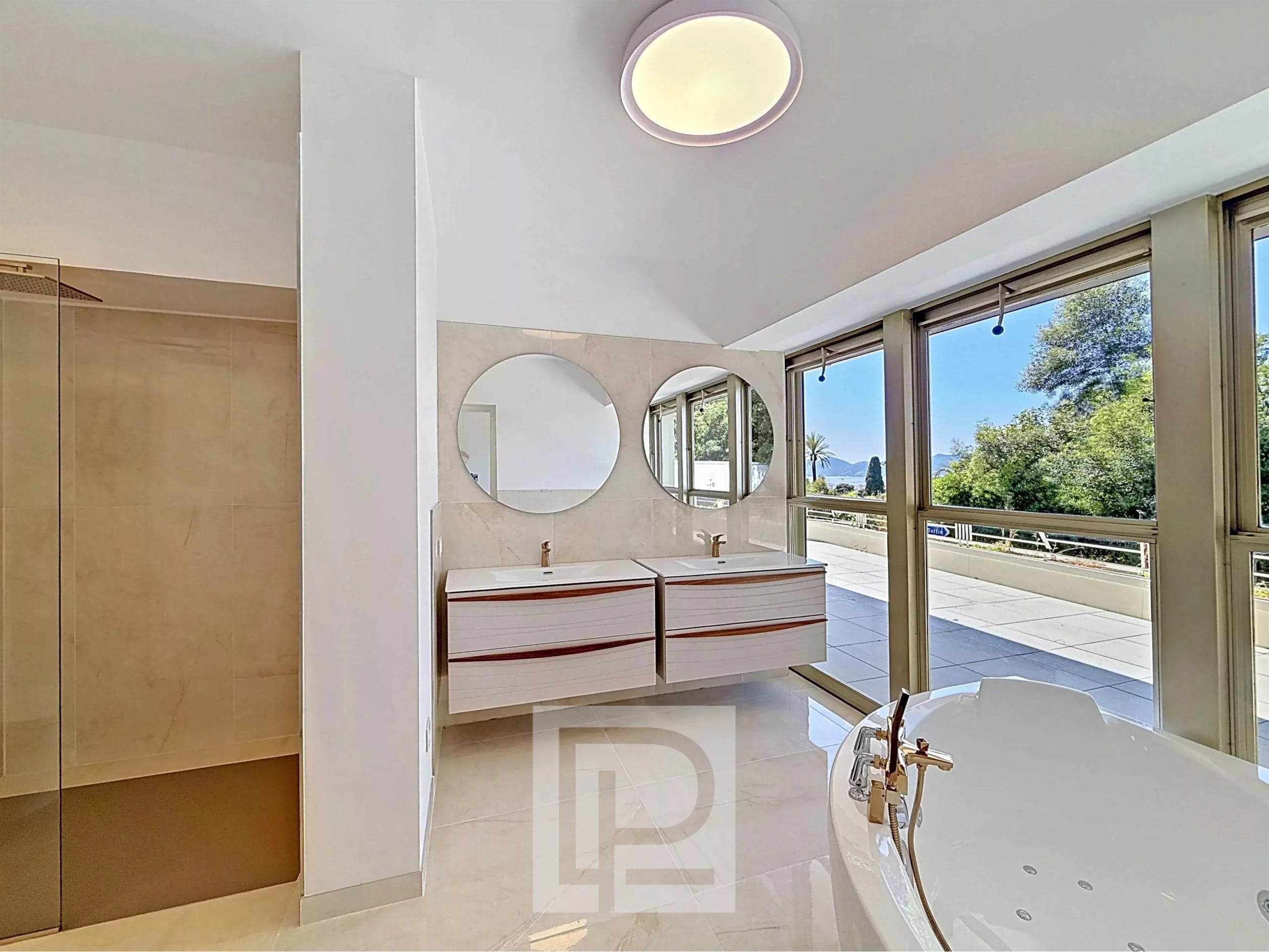 Modern bathroom with double sink and bathtub, large windows offering a view of the park.