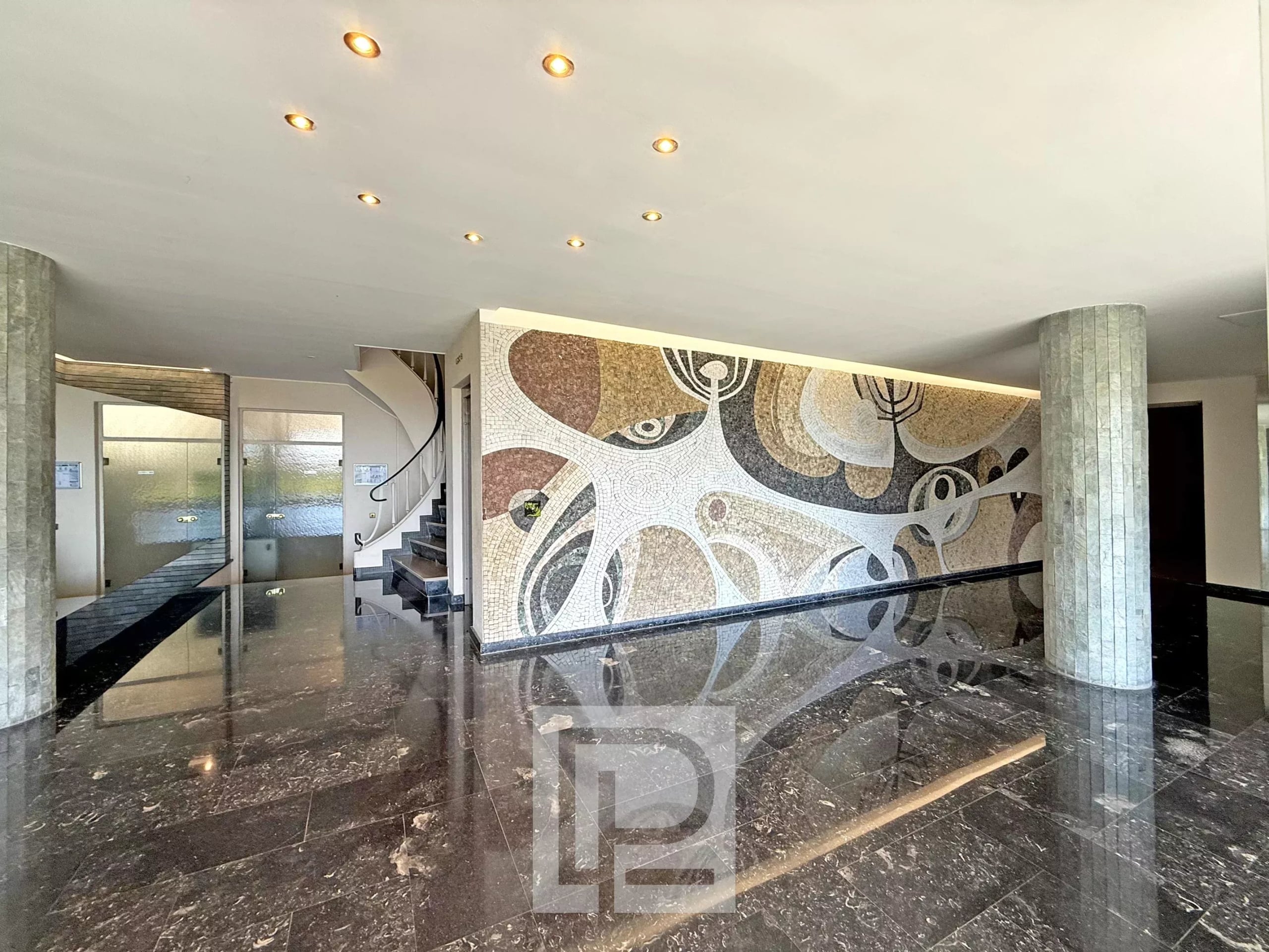 Entrance hall of a luxury residence with a marble floor and mosaic wall decoration.