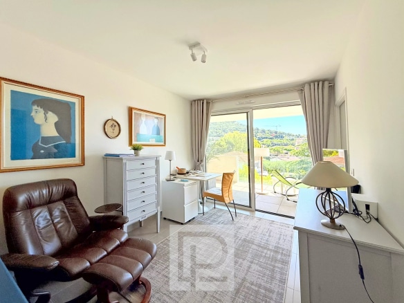 Intérieur d'un appartement avec vue sur les collines et la mer, mobilier moderne et lumineux.
