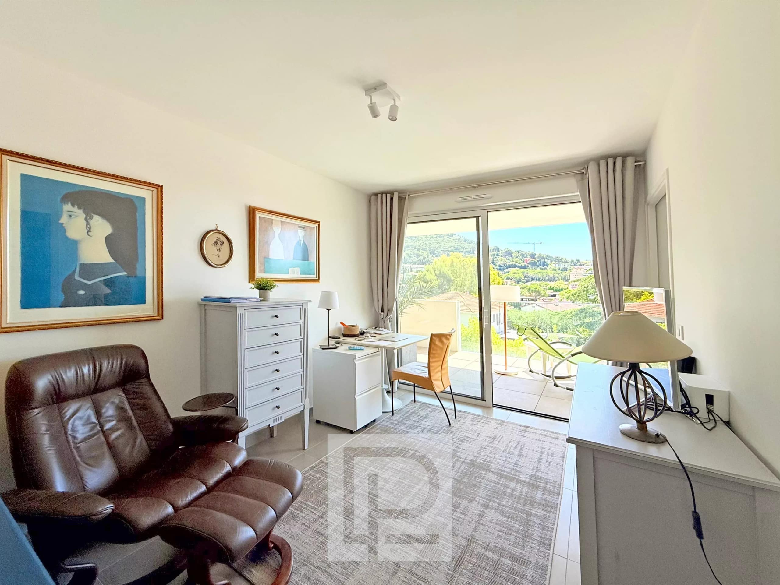 Intérieur d'un appartement avec vue sur les collines et la mer, mobilier moderne et lumineux.