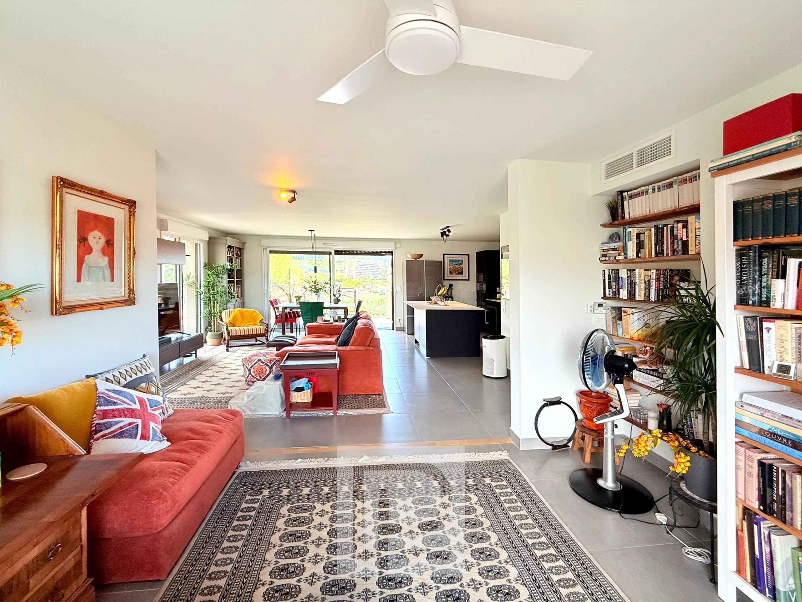 Intérieur d'un appartement moderne avec salon lumineux et vue sur les collines et la mer.
