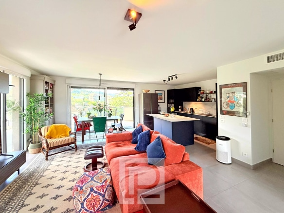 Intérieur d'un appartement moderne avec salon, cuisine ouverte et accès à un balcon.