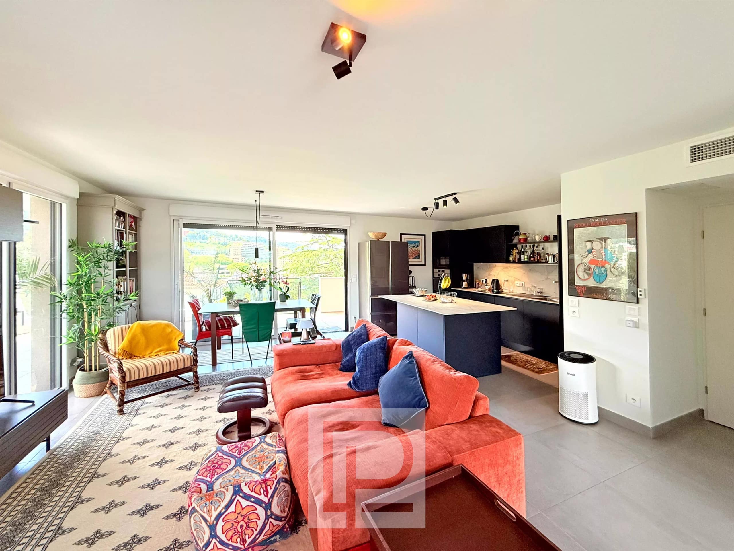 Intérieur d'un appartement moderne avec salon, cuisine ouverte et accès à un balcon.