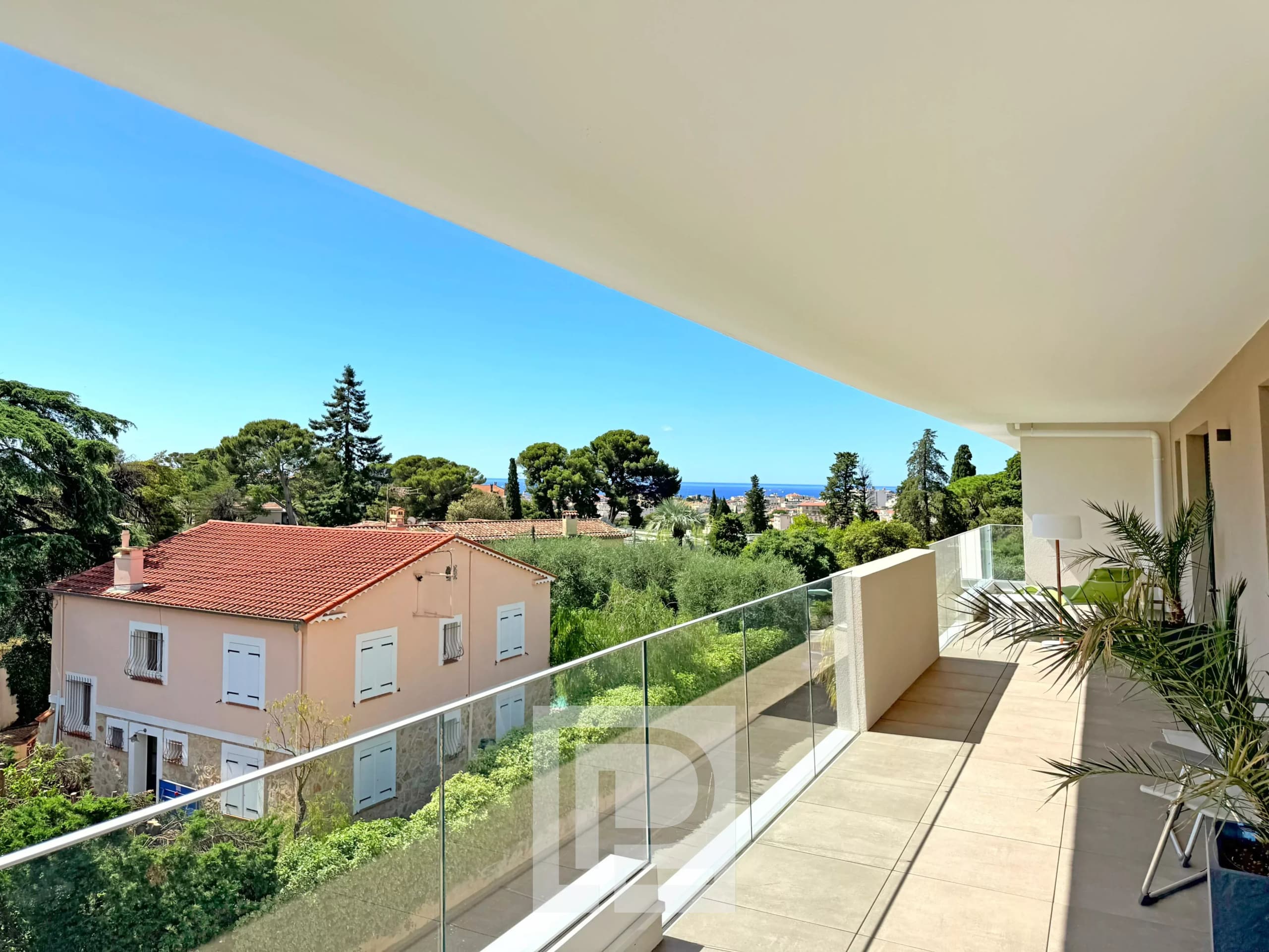 Balcon d'un appartement avec vue sur collines et mer, entouré de verdure au Cannet.