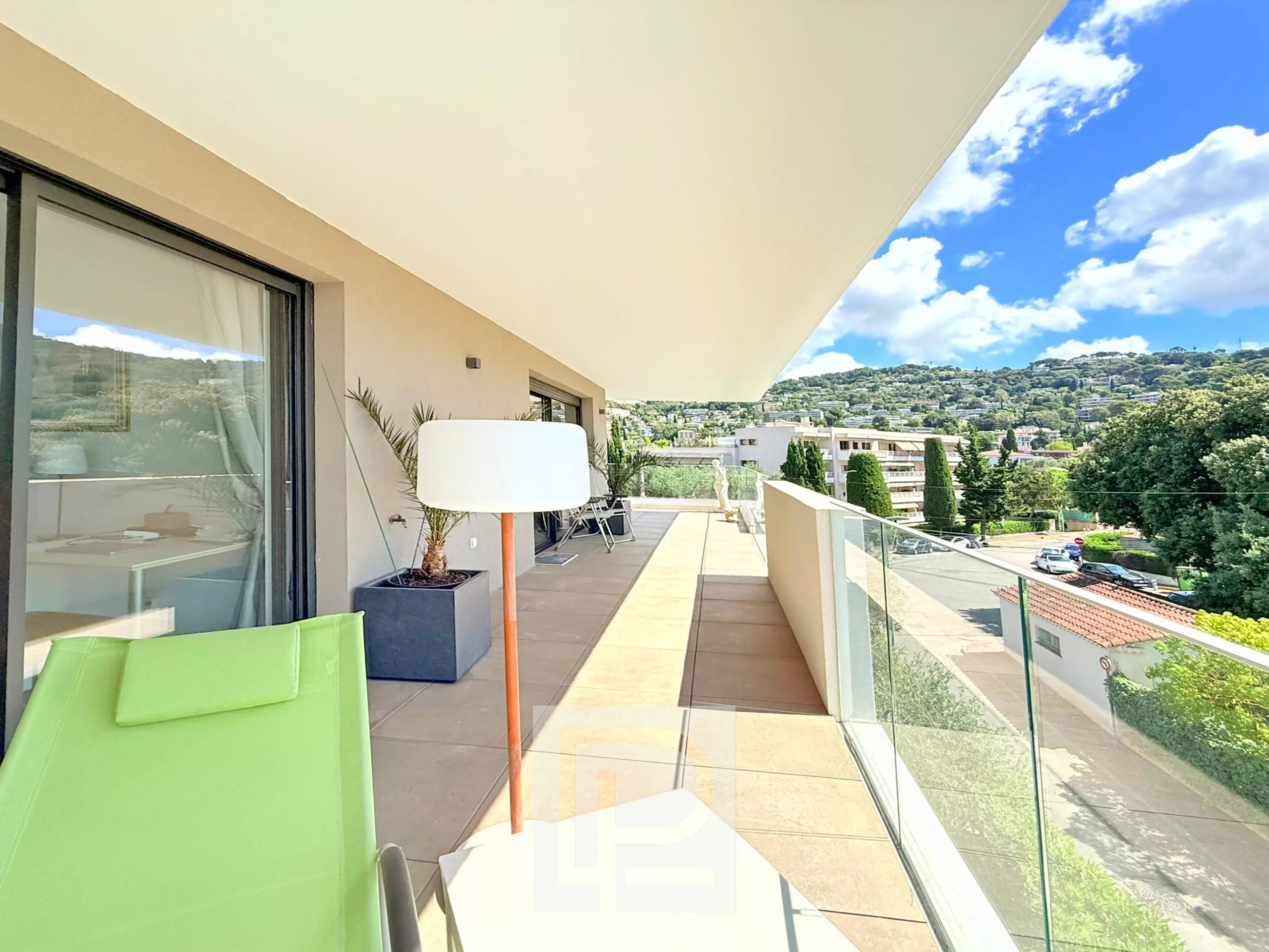Terrasse d'un appartement avec vue sur collines et mer, mobilier moderne, ciel bleu à Le Cannet.