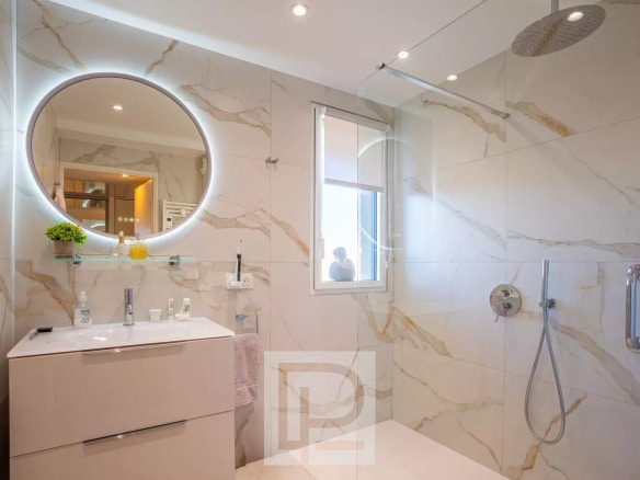 Salle de bain moderne avec douche à l'italienne et miroir rond lumineux.