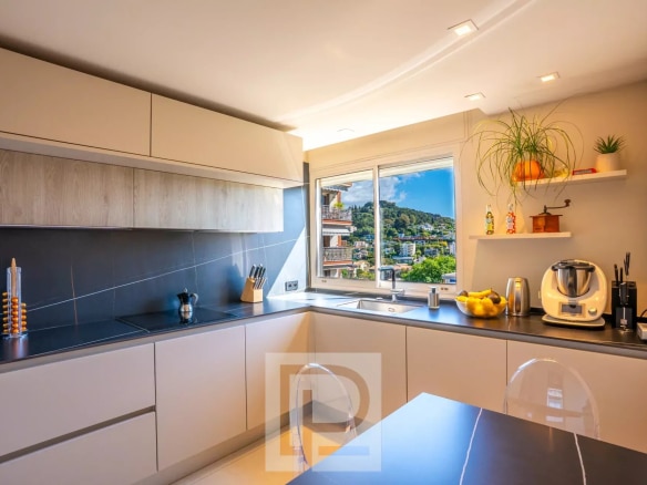 Cuisine moderne et lumineuse d'un appartement rénové avec vue sur le paysage.