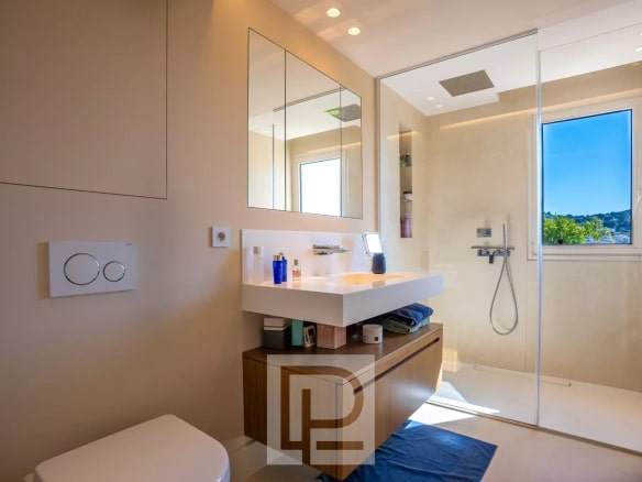 Salle de bain moderne avec douche et meuble sous vasque dans un appartement rénové.