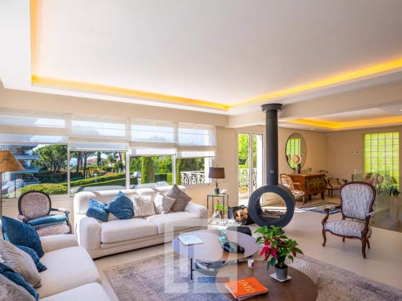 Salon lumineux d'un appartement rénové avec des meubles modernes et une vue sur l'extérieur.