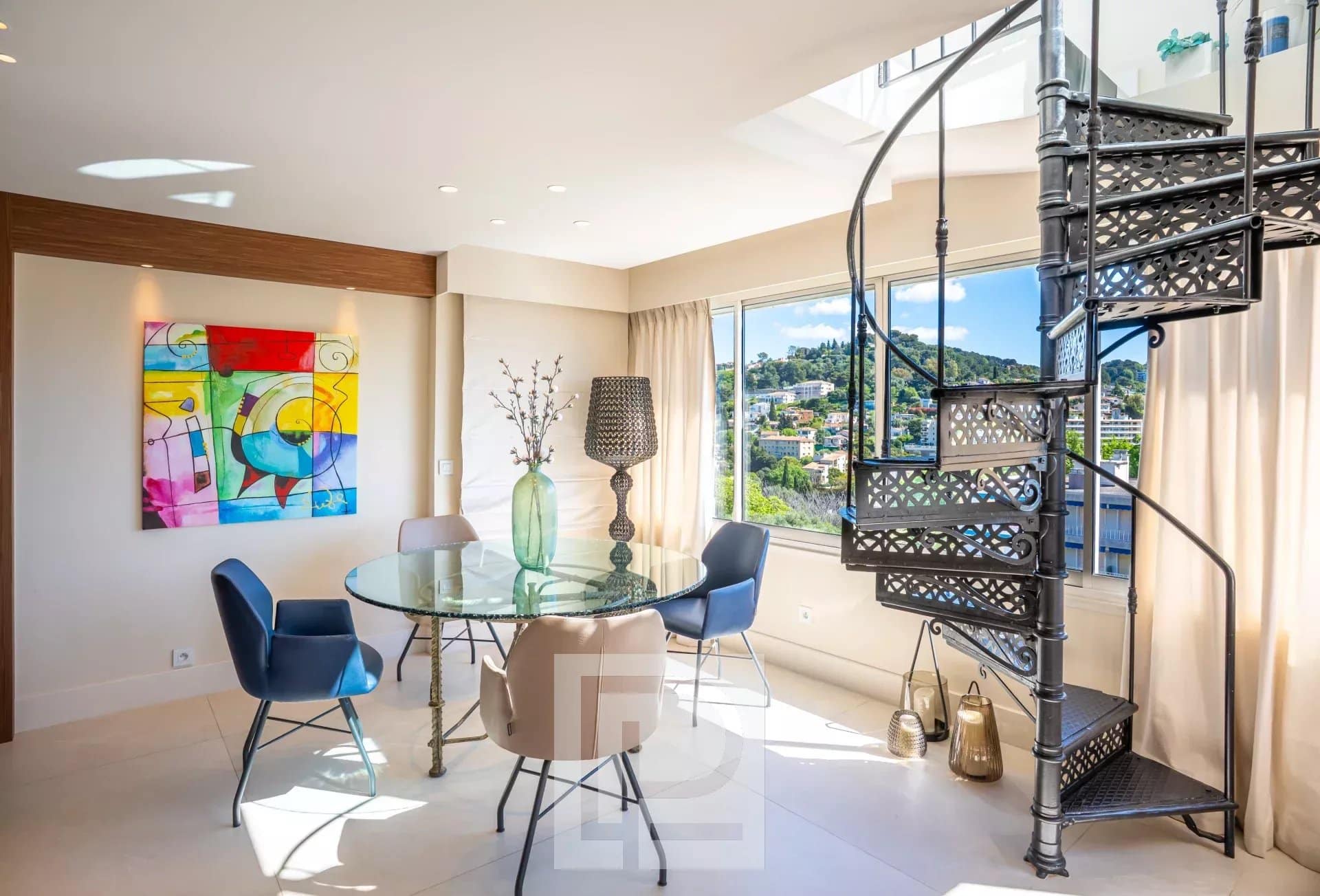 Appartement rénové au dernier étage à Le Cannet Intérieur d'un appartement rénové avec table ronde et escaliers en colimaçon, vue sur la ville.
