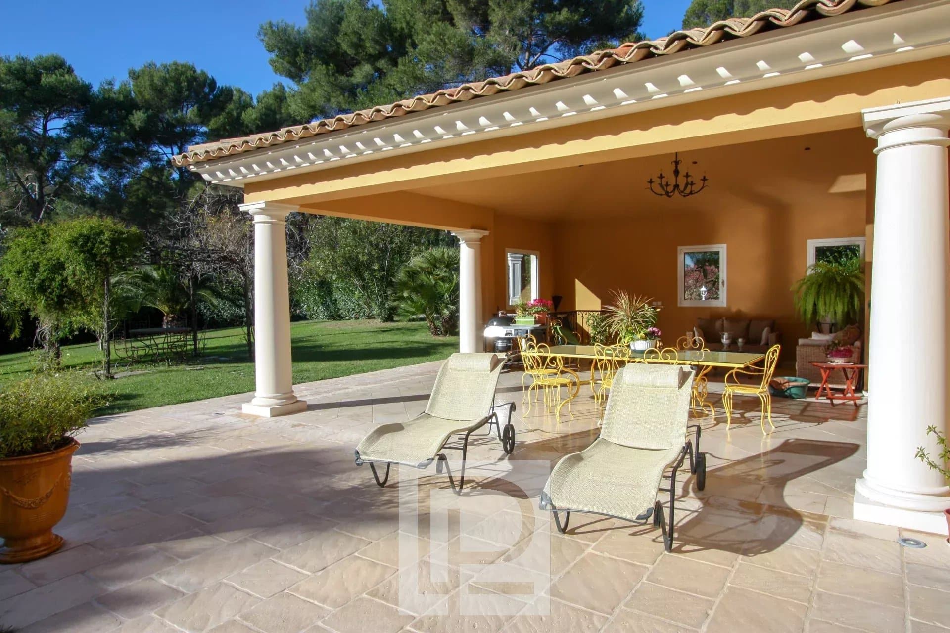 Terrasse de villa à Mougins Terrasse d'une villa à Mougins avec chaises longues et vue sur un jardin paysagé.