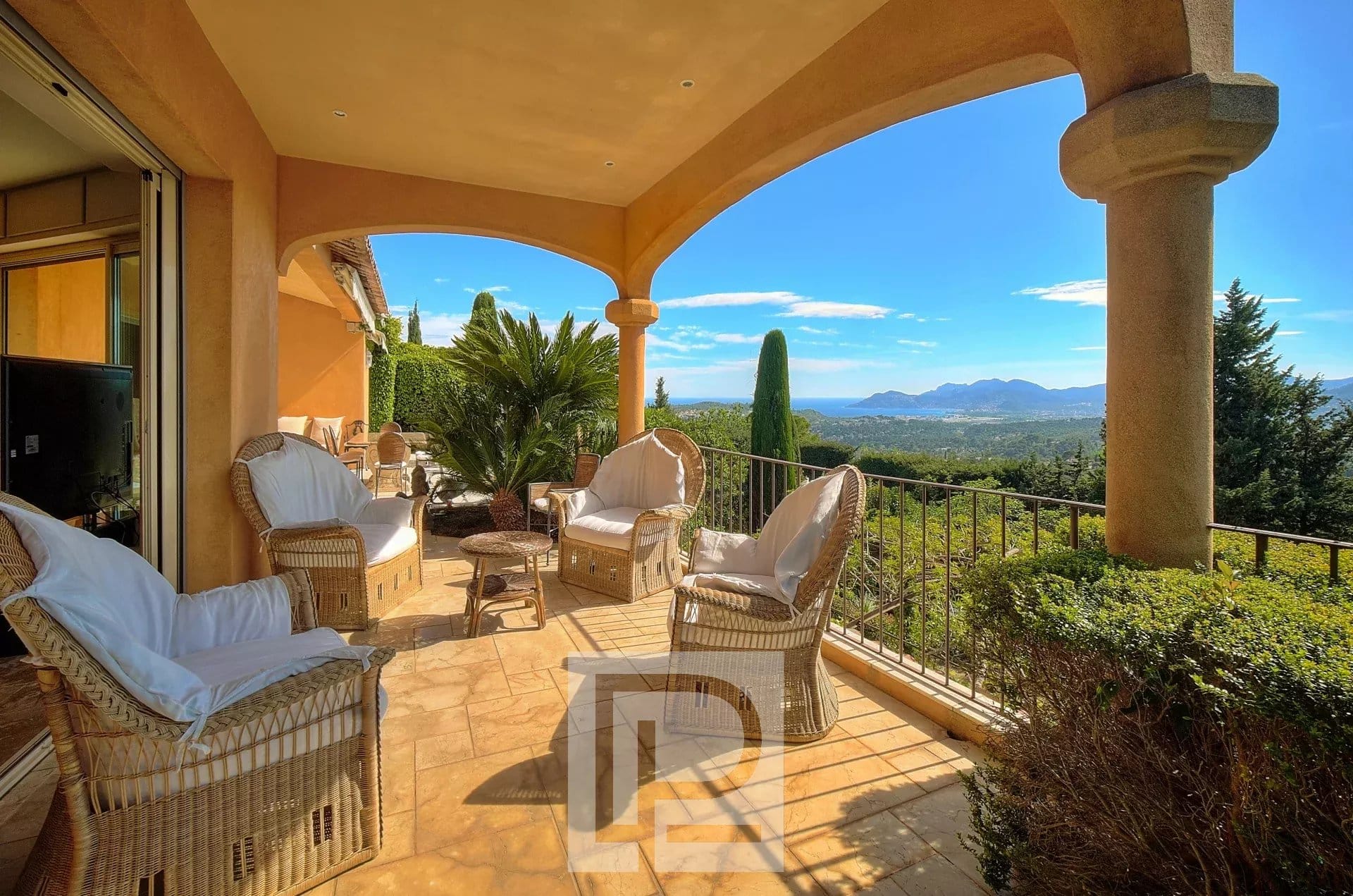 Terrasse d'une villa à Mougins avec vue panoramique sur la mer et l'arrière-pays, meubles en osier.