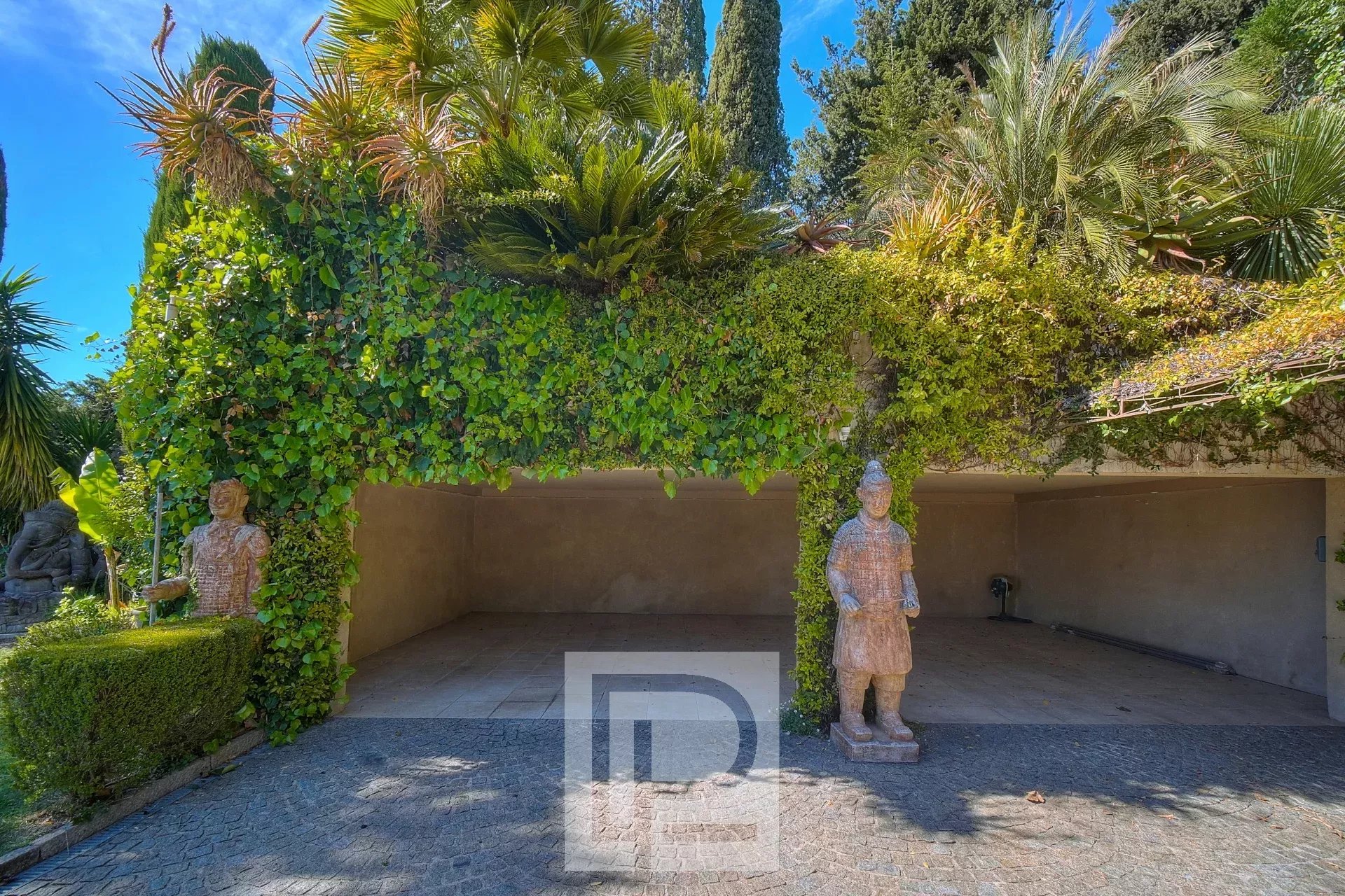 Entrée d'une propriété avec des statues et de la végétation luxuriante à Mougins.