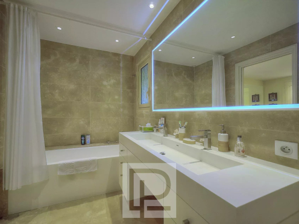 Salle de bain moderne avec baignoire, lavabo et miroir lumineux.