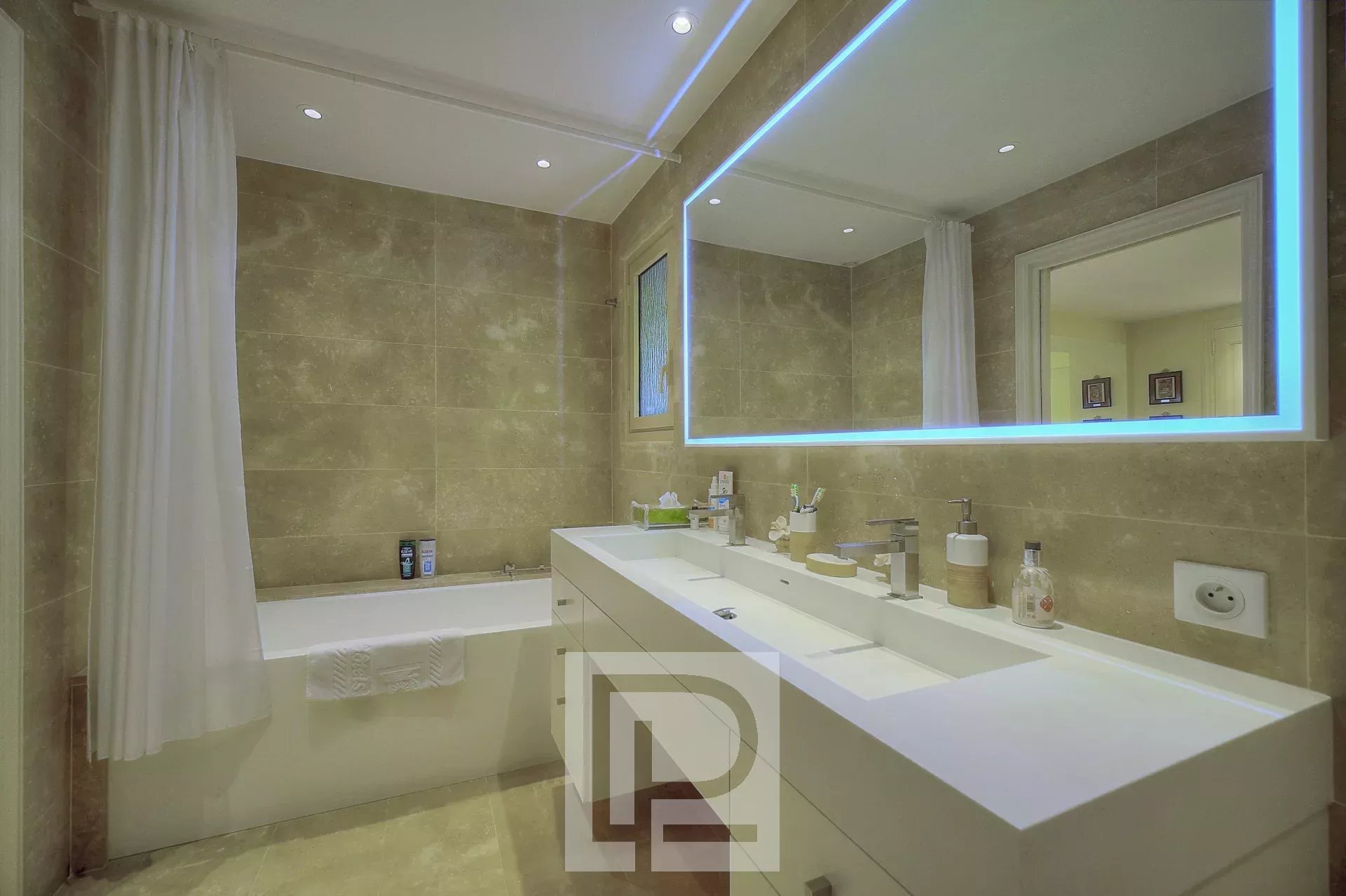 Salle de bain moderne avec baignoire, lavabo et miroir lumineux.