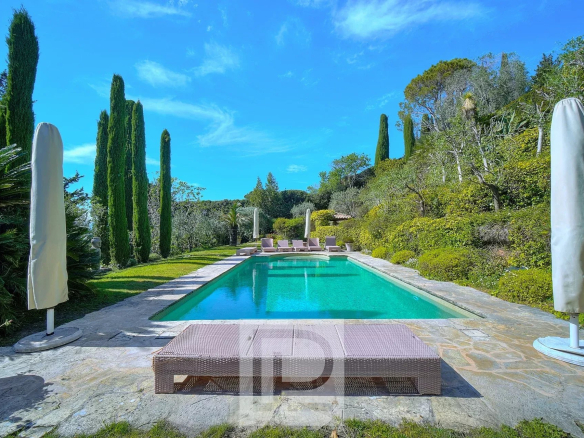 Piscine entourée de verdure dans une villa à Mougins avec vue panoramique sur la mer et l'arrière-pays.